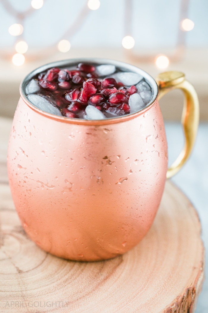 Delicious Pomegranate Moscow Mule Recipe with Pama Liqueur - served in a copper mug with ginger beer, ginger bee, vodka, and pomegranate seeds 